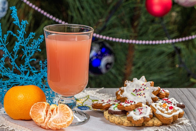 Bicchiere di succo di mandarini e un abete con ornamenti natalizi