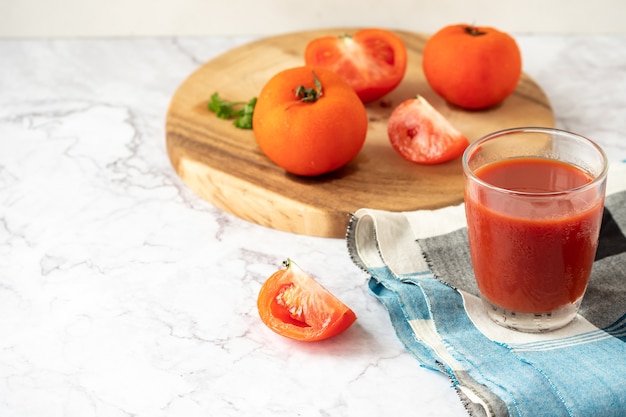 Bicchiere di succo di pomodoro e pomodori freschi sul tavolo di marmo. copia spazio