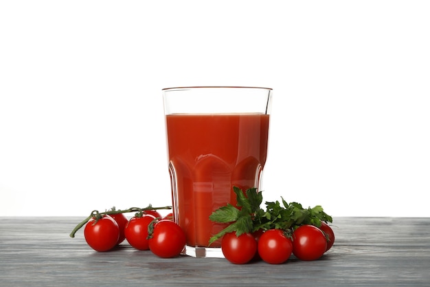 Bicchiere di succo di pomodoro e pomodori sul tavolo di legno isolato su bianco