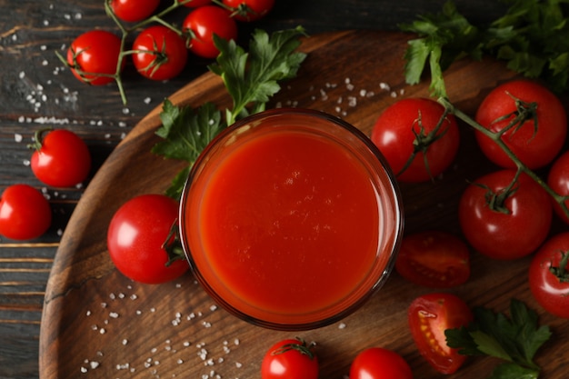 Bicchiere di succo di pomodoro, pomodori e sale su tavola di legno