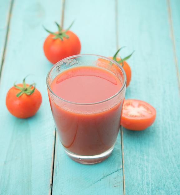 Bicchiere di succo di pomodoro sul tavolo di legno blu