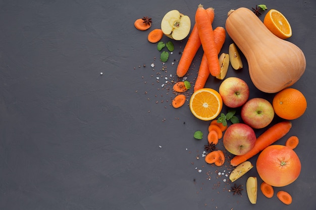 Bicchiere di succo o frullato fatto in casa, frutta e verdura. Carota fresca, mela, zucca, arancia, pompelmo sul tavolo scuro. Alimentazione sana, cibo, dieta, disintossicazione e concetto vegetariano.