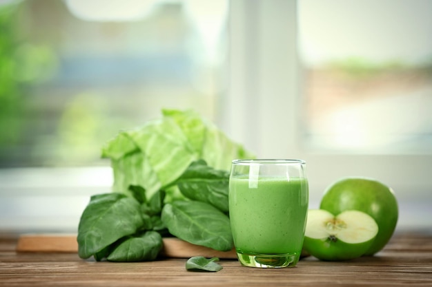 Bicchiere di succo verde sano con ingredienti sul tavolo di legno