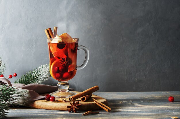 Bicchiere di vin brulè con ingredienti su un tavolo di legno