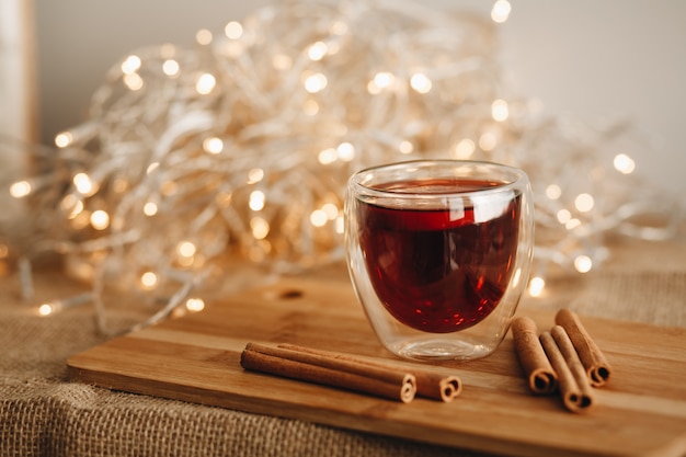 Bicchiere di vin brulè sul ceppo di legno con bastoncini di cannella