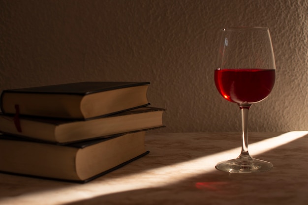 Bicchiere di vino accompagnato da alcuni libri con la luce di vendita che entra di lato
