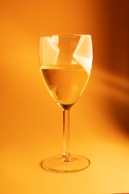 Bicchiere di vino bianco su sfondo arancione con luci sul vetro