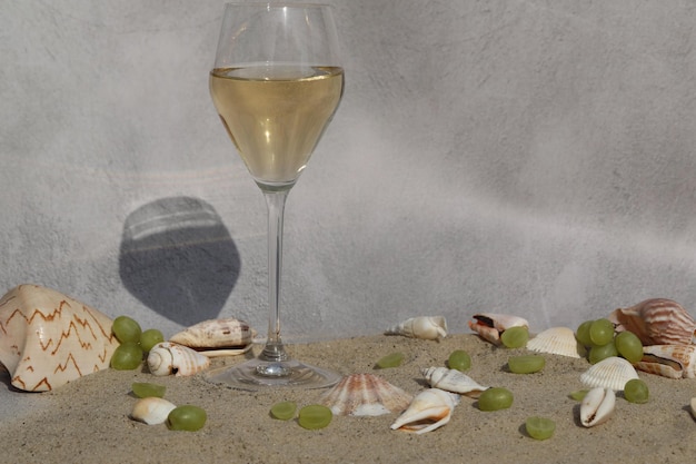 bicchiere di vino bianco sulla sabbia come sfondo con conchiglie