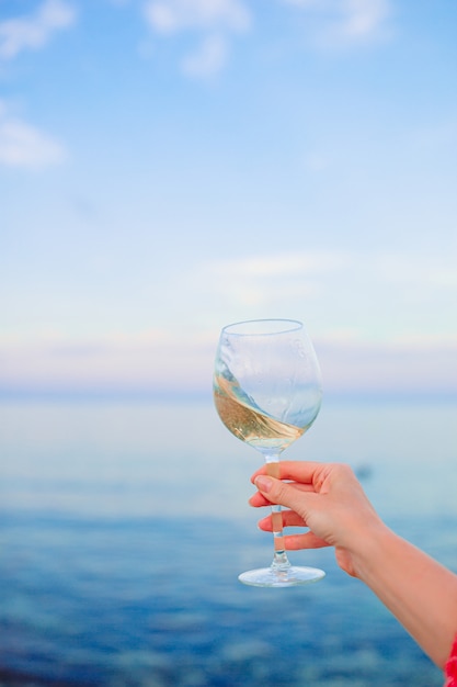 Bicchiere di vino bianco sulla spiaggia tropicale sul tramonto