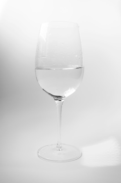 Bicchiere di vino con acqua sulla parete bianca. Bevanda analcolica di lusso ed eleganza