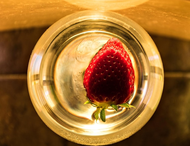 Bicchiere di vino con fragola che galleggia all'interno.