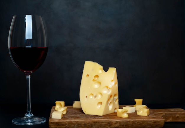 bicchiere di vino e gustoso formaggio su un tagliere, pietra di sfondo