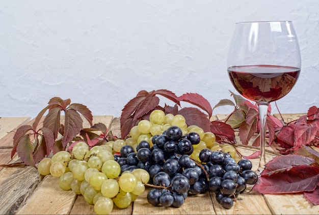 Bicchiere di vino rosso con molti grappoli d'uva