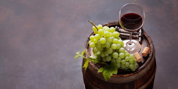 Bicchiere di vino rosso e uva bianca sulla vecchia botte