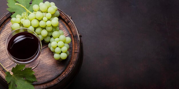 Bicchiere di vino rosso e uva bianca sulla vecchia botte