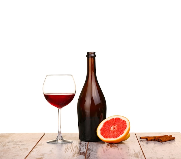 Bicchiere di vino rosso, una bottiglia di vino e pompelmo a bordo isolato su bianco