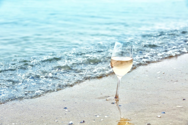 Bicchiere di vino sul primo piano della riva del mare