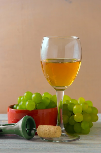 Bicchiere di vino, uva verde sul piatto sul tavolo.