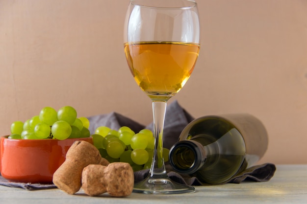 Bicchiere di vino, uva verde sul piatto sul tavolo.