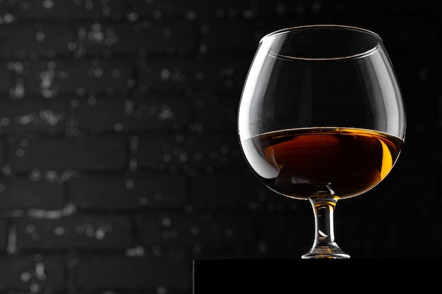 Bicchiere di whisky contro il muro nero scuro del grunge