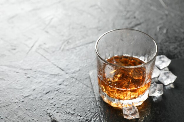 Bicchiere di whisky e cubetti di ghiaccio su sfondo nero, copia spazio