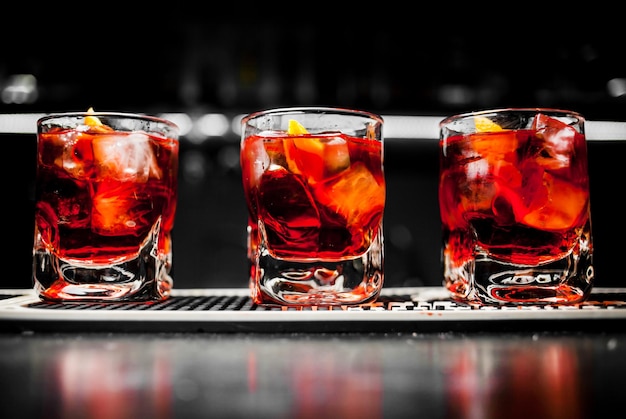 Bicchiere di whisky scozzese e ghiaccio sullo sfondo del cocktail alcolico rosso bar