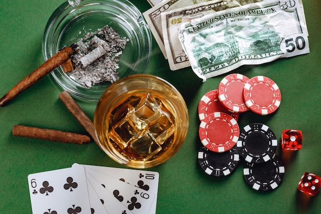 Bicchiere di whisky sigaro carte da gioco e fiches sulla superficie verde