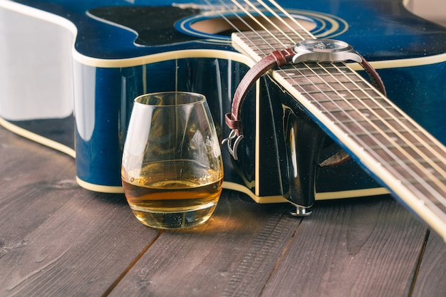 Bicchiere di whisky sul tavolo e chitarra