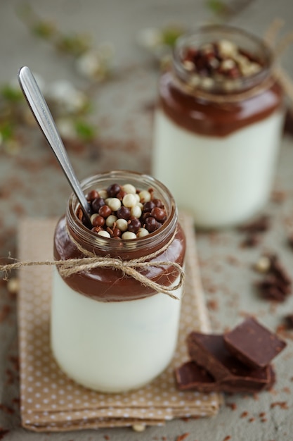 Bicchiere di yogurt fatto in casa con mousse al cioccolato e cioccolata caramellata e cucchiaio.