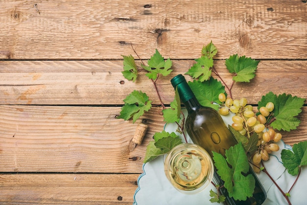 Bicchiere e bottiglia di vino bianco e uva fresca sullo spazio della copia del fondo di legno