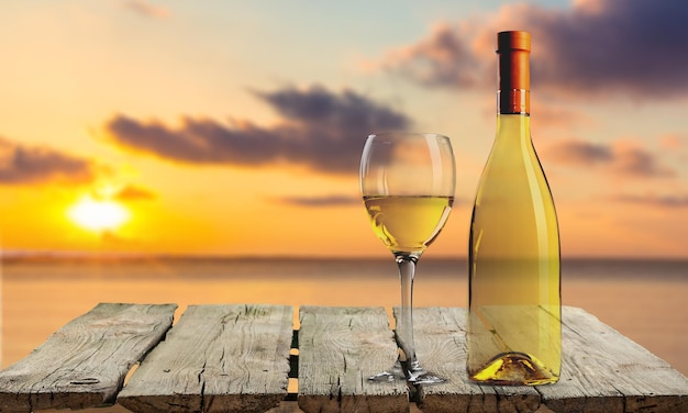 Bicchiere e bottiglia di vino bianco su fondo di legno