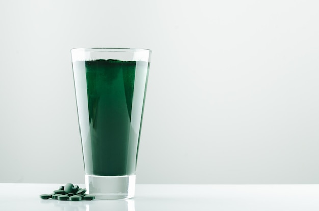 bicchiere minimalista con acqua e polvere di spirulina