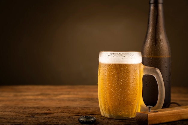 Bicchiere pieno di birra fredda sul tavolo di legno