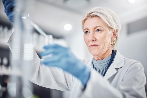 Bicchiere scientifico e pipetta per donna anziana in laboratorio per la ricerca medica Innovazione scienziata e anziana dottoressa che sperimenta analisi o test e ricerca sulla cura del virus con contagocce