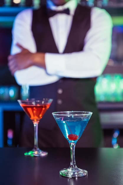 Bicchieri blu e arancioni di cocktail sul bancone bar e barista