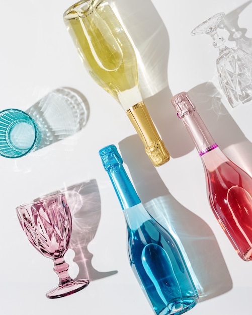Bicchieri colorati per vino e bottiglia di spumante con la luce del sole