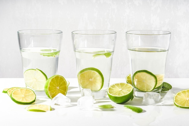 Bicchieri con acqua, fette di lime, menta e cubetti di ghiaccio