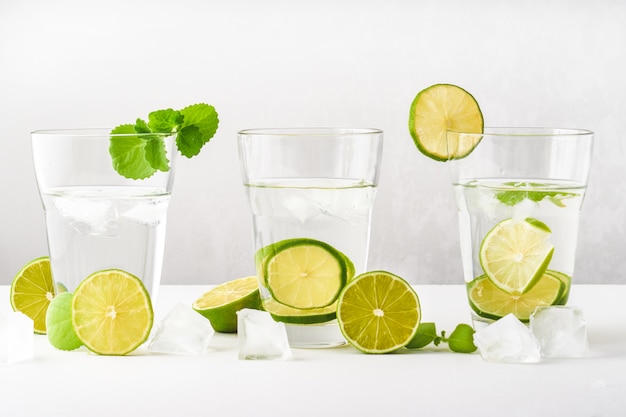 Bicchieri con acqua, fette di lime, menta e cubetti di ghiaccio