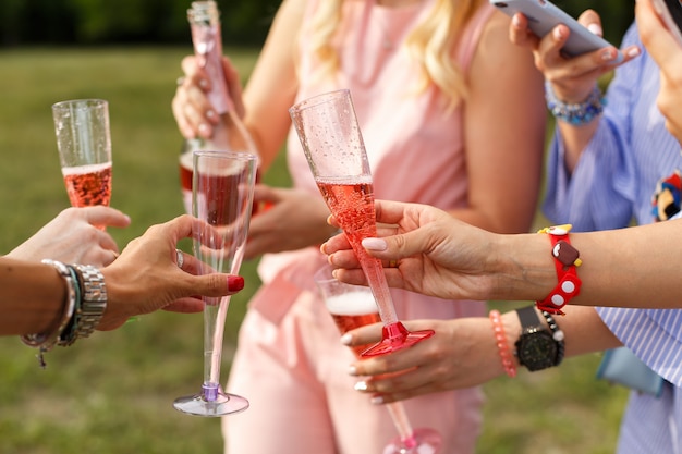 Bicchieri con champagne nelle mani. Il picnic della donna al parco di domenica.