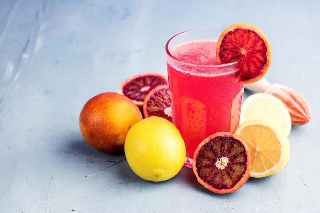 Bicchieri con limonata di arancia rossa e limone Posto per il testo Sfondo blu