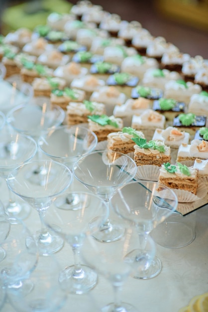 Bicchieri da cocktail vuoti e pezzi di torte stanno sul tavolo bianco