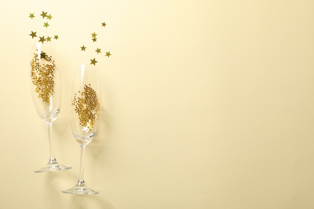 Bicchieri di champagne con glitter su beige, spazio per il testo