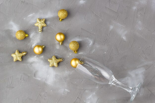 Bicchieri di champagne con palline d'oro e stelle su sfondo grigio, copia dello spazio. Natale Capodanno concetto. Vista dall'alto, posizione piatta