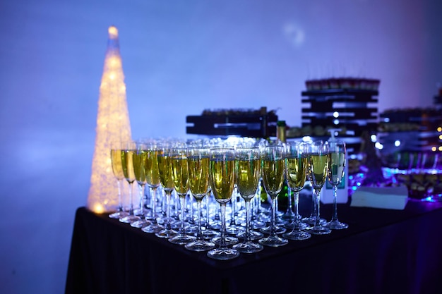 Bicchieri di champagne meravigliosamente luminosi sul tavolo sullo sfondo di un'atmosfera festosa con illuminazione al neon.