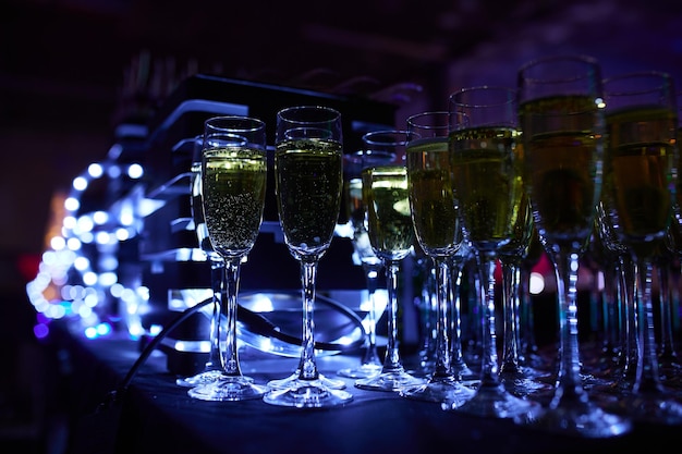 Bicchieri di champagne meravigliosamente luminosi sul tavolo sullo sfondo di un'atmosfera festosa con illuminazione al neon.
