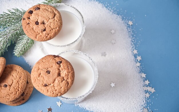 Bicchieri di latte, biscotti, ramo dell'albero di Natale sui precedenti blu