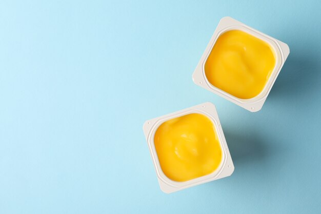 Bicchieri di plastica di yogurt giallo sull'azzurro