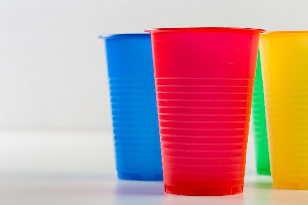 Bicchieri di plastica monouso multicolori isolati su sfondo bianco