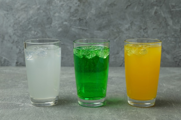 Bicchieri di soda diversa sulla superficie grigia