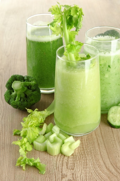 Bicchieri di succo di verdura verde su legno